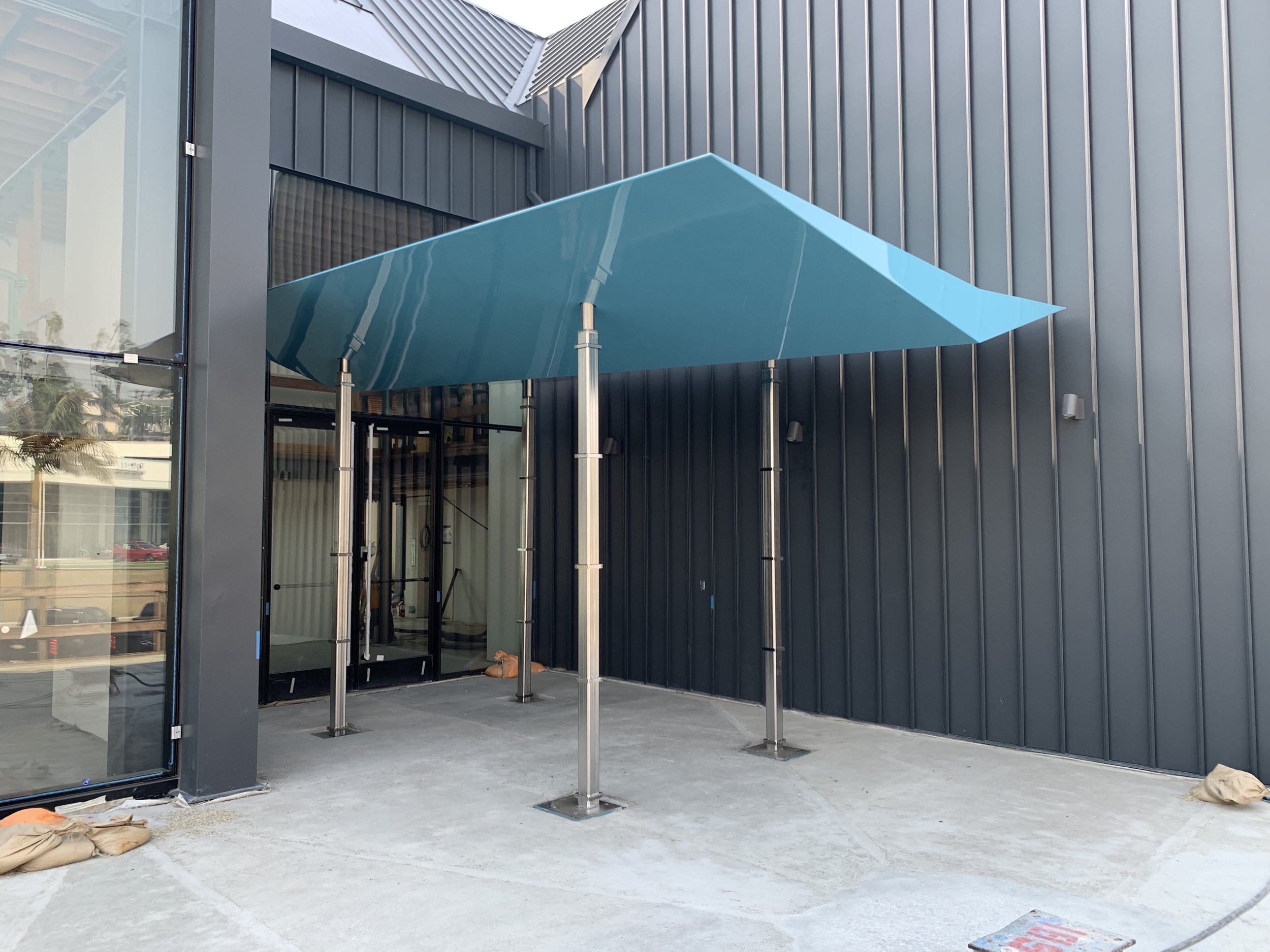 Modern entrance with blue awning and glass doors